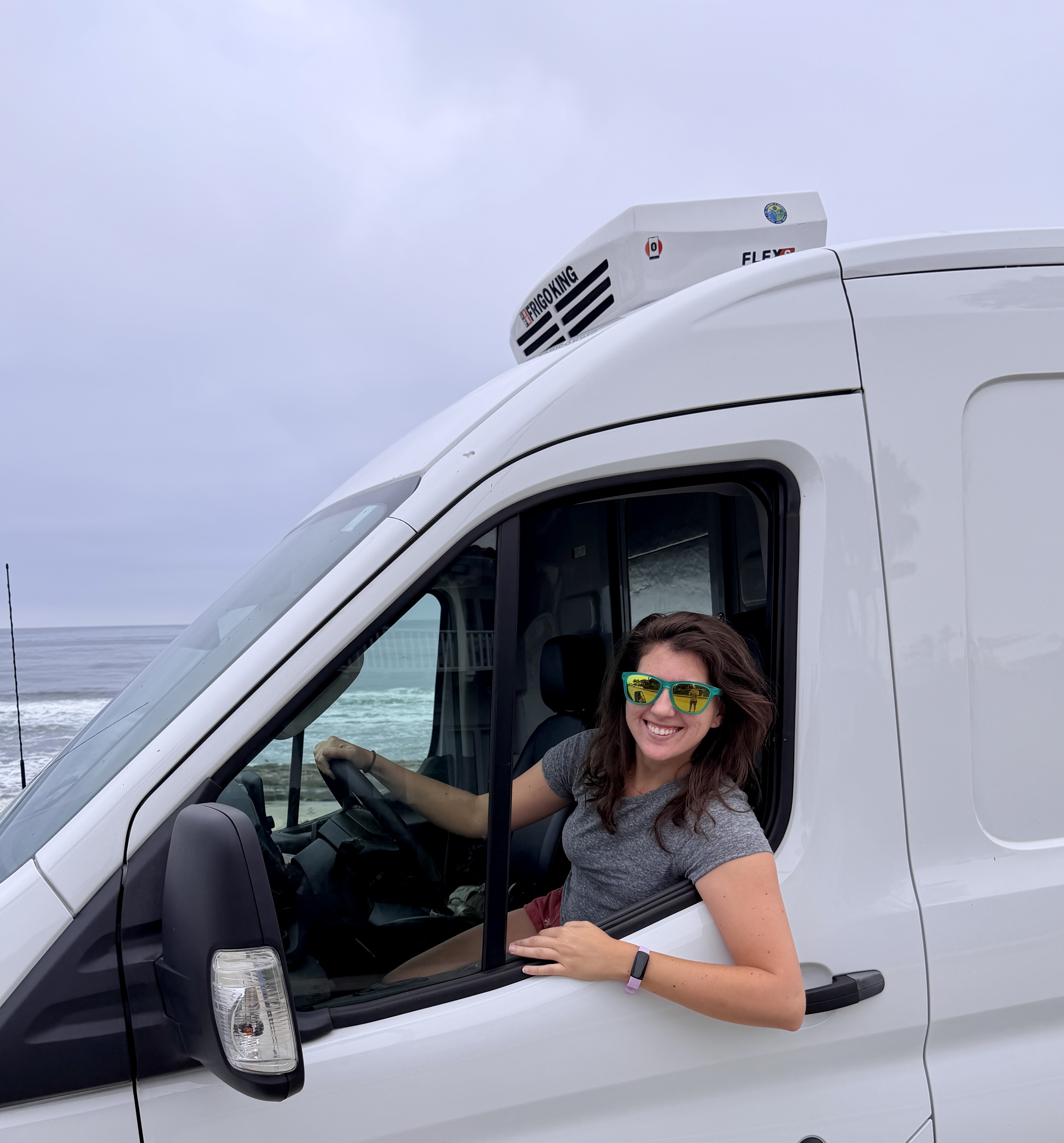 A Perpetual founder smiling in the cab of a refrigerated delivery van by the coast